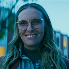 Uśmiechnięta Toni Collette w okularach, znana z wielu filmów, seriali i programów, wygląda na zadowoloną.