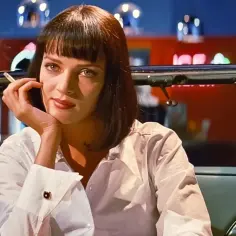 Uma Thurman w białej koszuli, z papierosem w dłoni, siedzi w samochodzie. Ikona z filmów Quentina Tarantino.