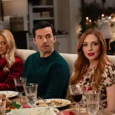 Lindsay Lohan w świątecznej komedii. Trzy osoby siedzą przy stole, na którym jest jedzenie.