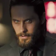 Jared Leto w filmach, z bladymi oczami i brodą, w garniturze.