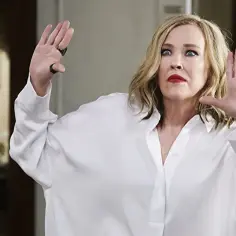 Catherine O'Hara w białej koszuli, z uniesionymi dłońmi, jakby w geście obrony. Ikona kina, znana z niezapomnianych ról w filmach, serialach i programach.
