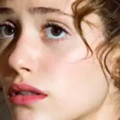 Zbliżenie na twarz Emmy Rossum, aktorki znanej z filmów, seriali i programów. Jej spojrzenie jest pełne emocji.