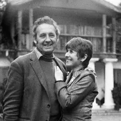 Uśmiechnięty Andrzej Wajda z żoną, Beatą Tyszkiewicz, na tle domu.