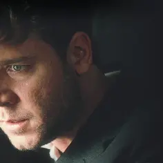 Russell Crowe w roli Johna Nasha, bohatera filmu "Piękny umysł", zamyślony, z intensywnym spojrzeniem.