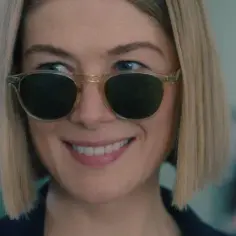 Uśmiechnięta Rosamund Pike w okularach przeciwsłonecznych, gwiazda filmów, seriali i programów.