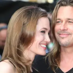 Angelina Jolie i Brad Pitt uśmiechają się do siebie na czerwonym dywanie.