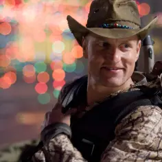 Woody Harrelson w kapeluszu kowbojskim, z pistoletami, w scenie z jednego z jego filmów.