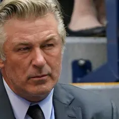 Alec Baldwin, znany z wielu niezapomnianych ról w filmach, w garniturze, z siwiejącymi włosami, spogląda w bok.