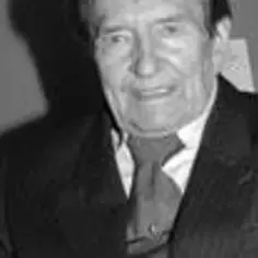 Portret Wieńczysława Glińskiego, uśmiechniętego, w garniturze. W tle widać fragment kraty.