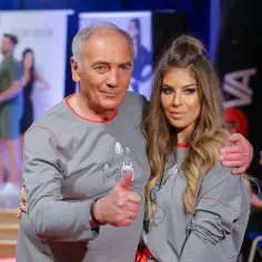Karol Strasburger z żoną, uśmiechnięci, w szarych bluzach z zabawnym nadrukiem. Karol pokazuje kciuk w górę.