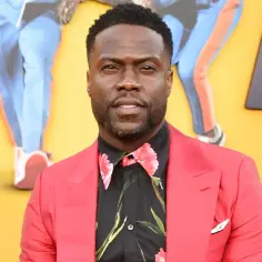 Kevin Hart w czerwonej marynarce i kwiecistej koszuli. Jego wzrost jest często tematem żartów, ale jego kariera jest imponująca.