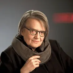 Portret Agnieszki Holland, reżyserki znanej z poruszających filmów, w okularach i z szalikiem.