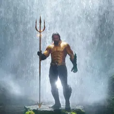 Jason Momoa jako Aquaman, bohater filmów i seriali, stoi z trójzębem pod wodospadem.