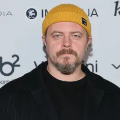 Tomasz Schuchardt w żółtej czapce i czarnym garniturze, znany z wielu filmów, seriali i programów.