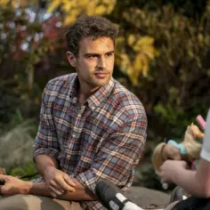 Theo James w kratowanej koszuli, w otoczeniu jesiennej przyrody. Jego filmy, seriale i programy to fascynujące historie.