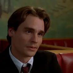 Robert Sean Leonard w garniturze, w tle czerwone siedzenia i zielona ściana z malowidłem. Jego filmy, seriale i programy to klasyka.