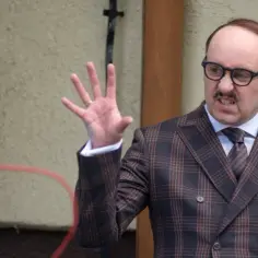 Adam Woronowicz w garniturze w kratę, z gestykulacją, jakby opowiadał o swoich filmach.