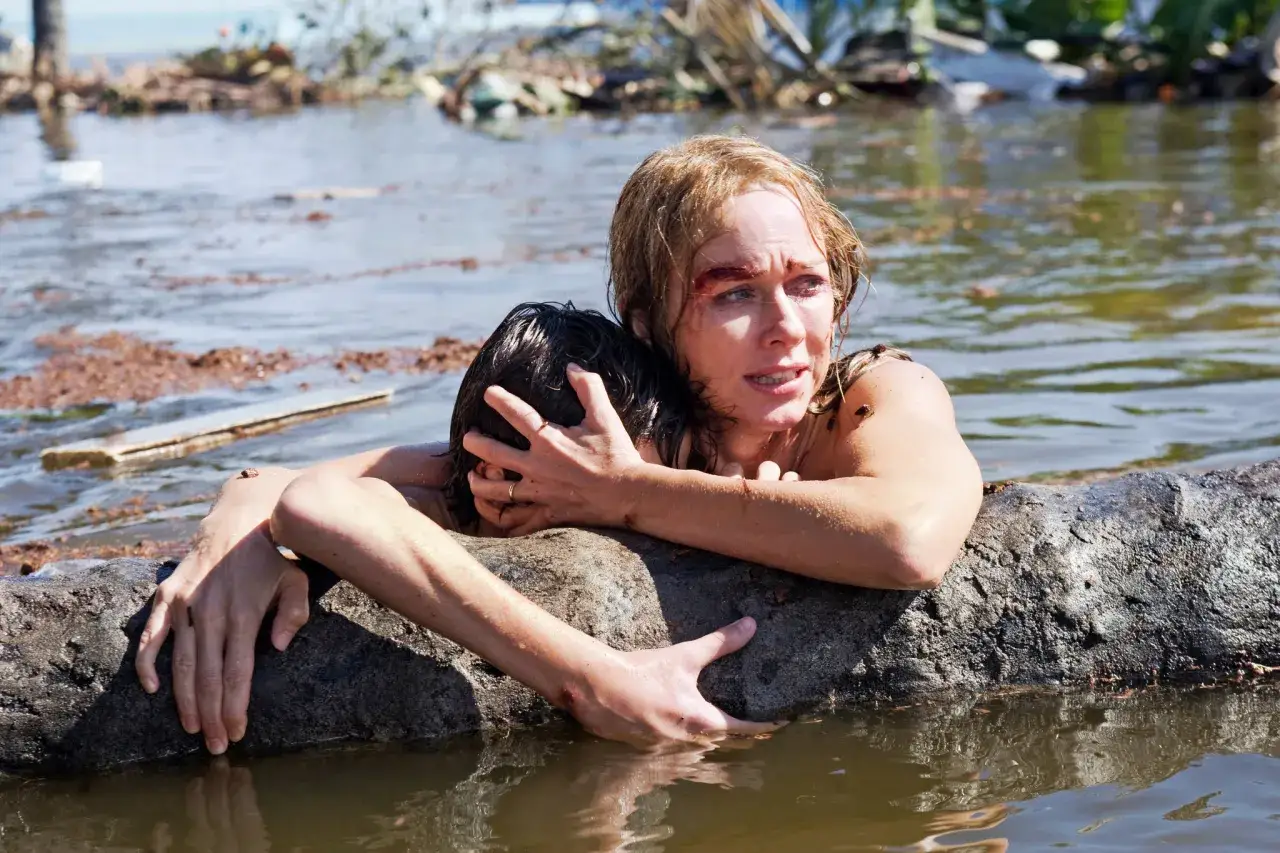 Naomi Watts w filmach walczy o przetrwanie, tuląc dziecko na zwalonym pniu w wodzie po katastrofie.
