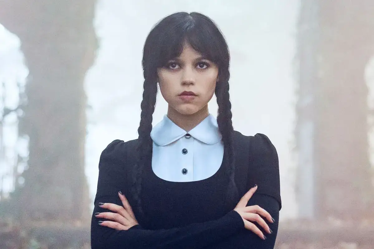 Jenna Ortega jako Wednesday, aktorka w czarnej sukience z białym kołnierzykiem, z włosami zaplecionymi w dwa warkocze.