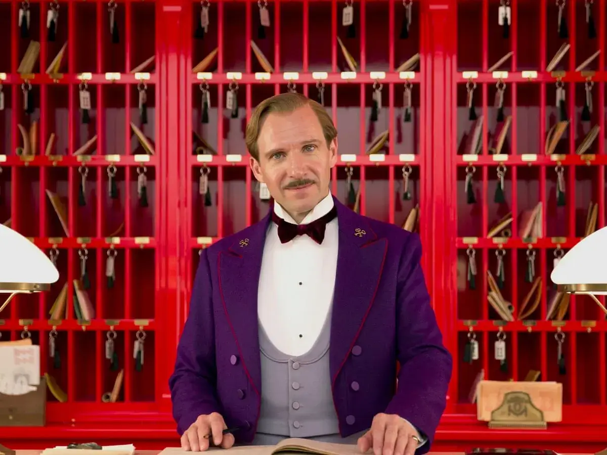 Ralph Fiennes w filmach, jako Monsieur Gustave H. w hotelu, z kluczami w tle.