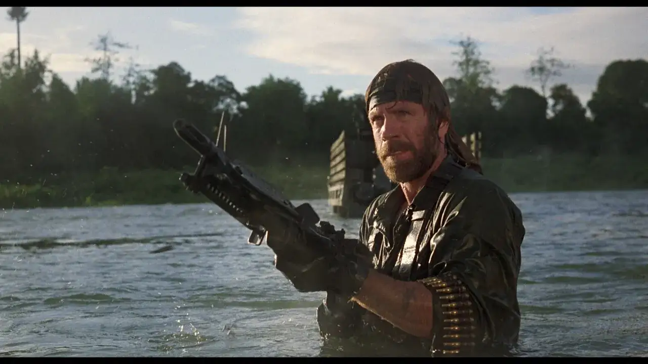 Chuck Norris w wodzie z karabinem maszynowym, gotowy do akcji w jednym ze swoich kultowych filmów.