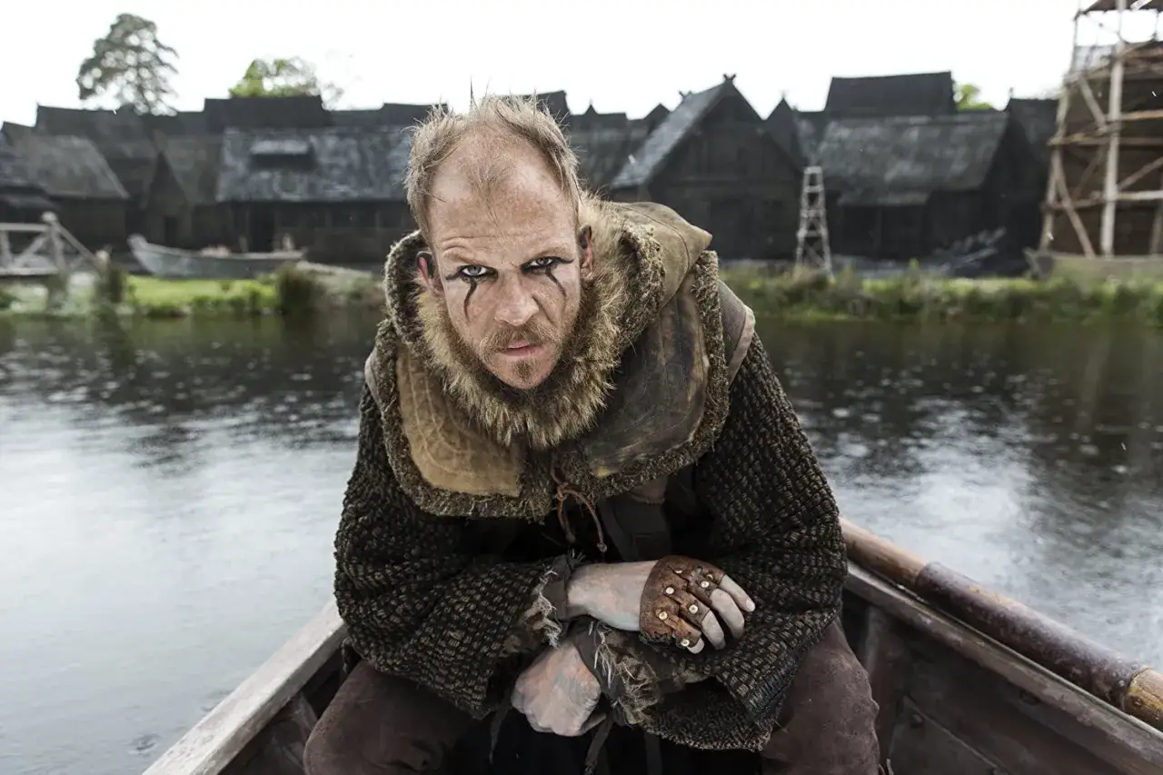 Floki w łodzi, z wojennym makijażem na twarzy, w zbroi i futrzanym kołnierzu, patrzy groźnie.