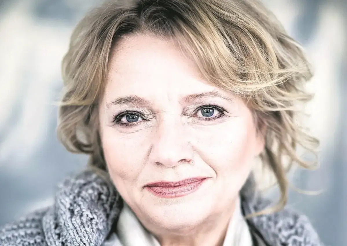 Portret polskiej aktorki po 40. z niebieskimi oczami i blond włosami, w szarym swetrze.