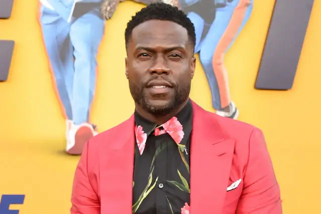Kevin Hart w czerwonej marynarce i kwiecistej koszuli. Jego wzrost jest często tematem żartów, ale jego kariera jest imponująca.